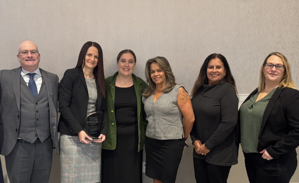 Photo of CLASI staff members standing and smiling with attorney Laura Graham at the 2025 DSBA Christopher White Access to Justice Awards.